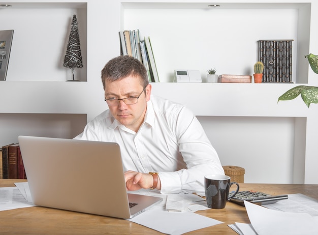 Geschäftsmann, der am Schreibtisch zu Hause Bürogeschäft arbeitet