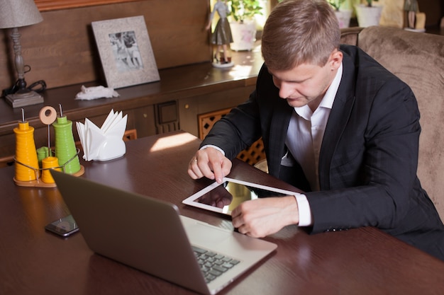 Geschäftsmann, der an einer Tablette in einem Café arbeitet