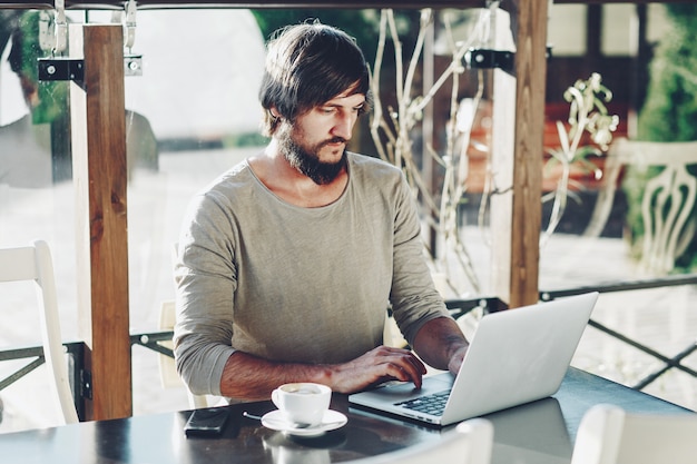 Geschäftsmann, der an seinem Computer am Café arbeitet