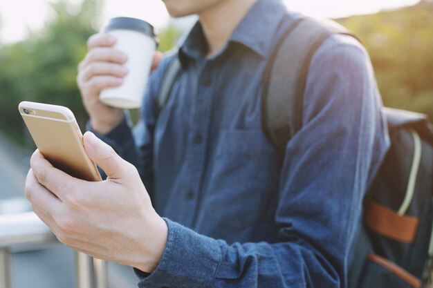 Geschäftsmann, der auf dem Smartphone spricht und trinkt, nimmt Kaffee an der Stadt weg.