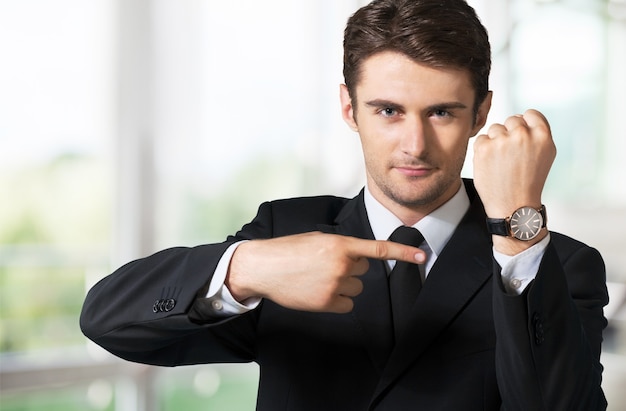 Foto geschäftsmann, der auf die handuhr im hintergrund zeigt