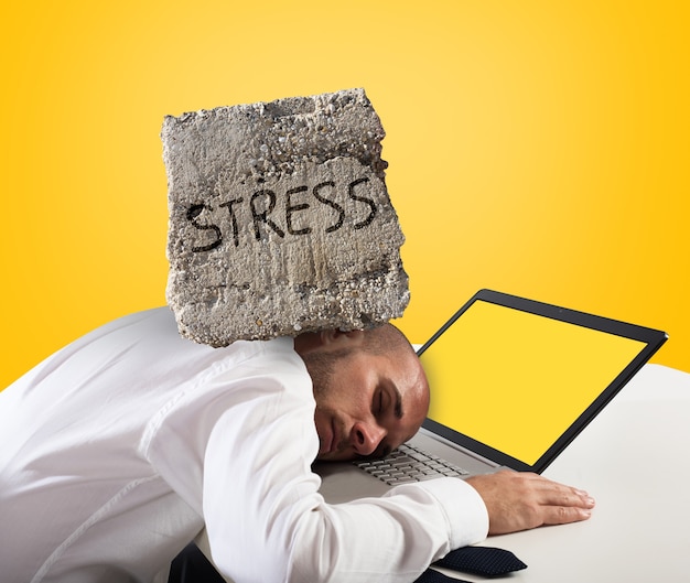 Geschäftsmann, der auf einem Computer schläft. Stress- und Überarbeitungskonzept. Gelber Hintergrund