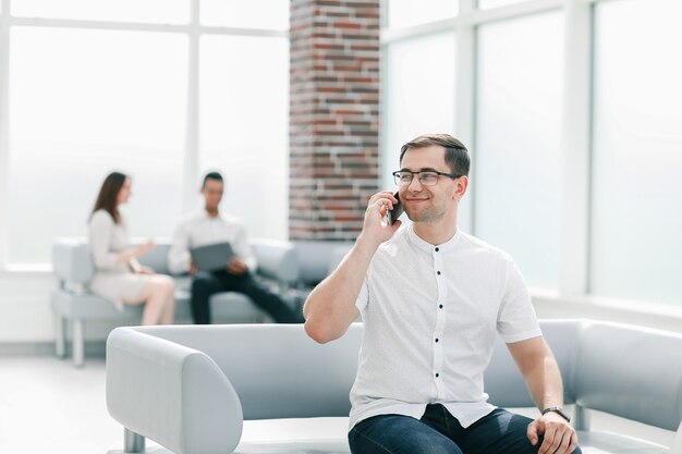 Geschäftsmann, der auf einem Mobiltelefon in der Lobby des Geschäftszentrums spricht. Unternehmenskonzept