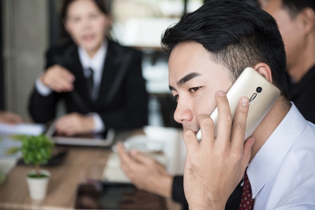 Geschäftsmann, der auf Smartphone in der Sitzung spricht.