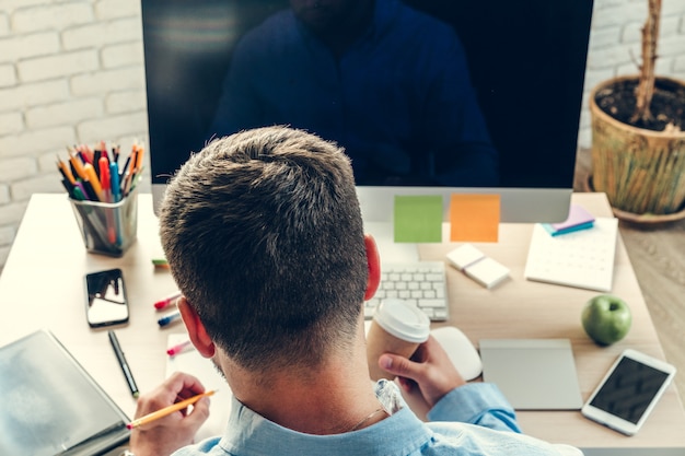 Geschäftsmann, der Computermonitor während des Arbeitstages im Büro betrachtet