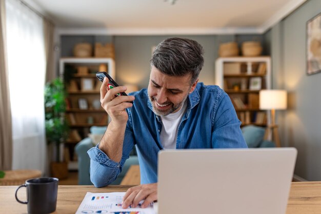 Foto geschäftsmann, der daten mit dem computer analysiert, während er im büro am telefon spricht, junger, grinsender, professioneller mann im büro