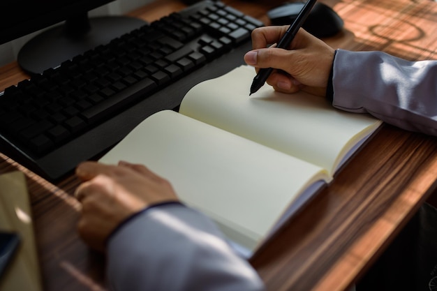 Geschäftsmann, der ein Buch bei der Arbeit liest und schreibt