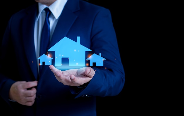 Geschäftsmann, der ein leuchtendes Haussymbol hält Immobilieninvestitions- und Finanzkonzepte