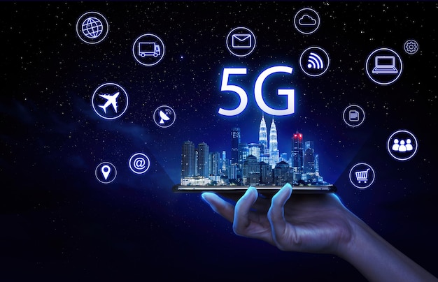 Geschäftsmann, der ein Mobiltelefon mit der intelligenten Stadt Kuala Lumpur und drahtlosen 5G-Netzwerksystemen und dem Internet der Dinge auf einem virtuellen Bildschirm hält