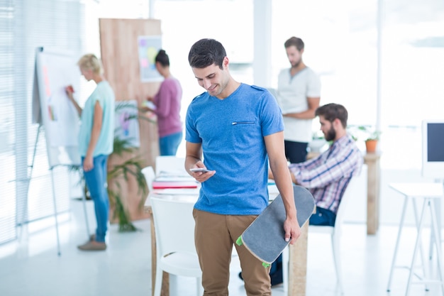 Geschäftsmann, der ein Skateboard im Büro hält