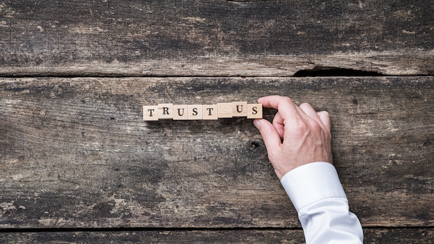 Foto geschäftsmann, der ein trust us-zeichen auf holzklötzen zusammenstellt.