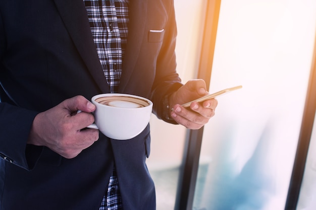 Geschäftsmann, der einen Anruf unter Verwendung eines intelligenten Telefons mit coffeee macht