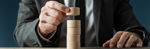 Geschäftsmann, der einen Stapel leere Holzschnittkreise baut