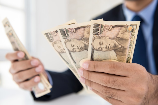 Geschäftsmann, der Geldbanknoten der japanischen Yen zählt