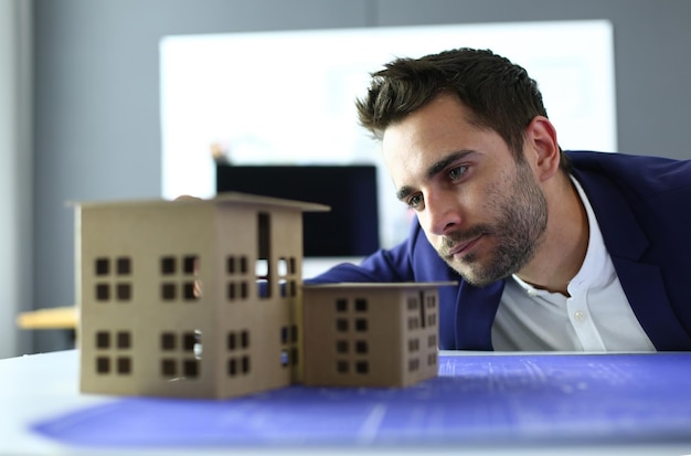 Geschäftsmann, der Hausminiatur auf der Hand hält, die im Büro steht