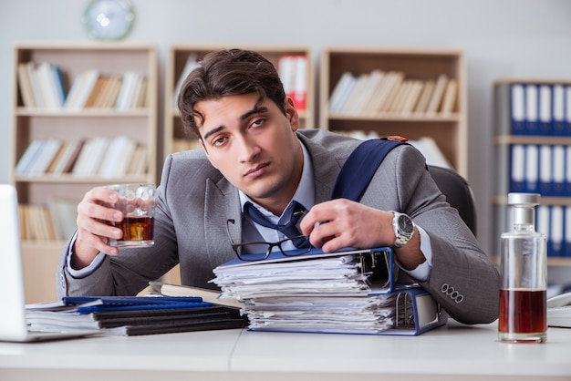 Geschäftsmann, der im Büro trinkt