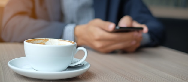 Geschäftsmann, der intelligentes Telefon in der Kaffeestube verwendet