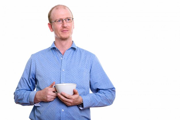 Geschäftsmann, der Kaffeetasse hält, während er auf Weiß isoliert denkt