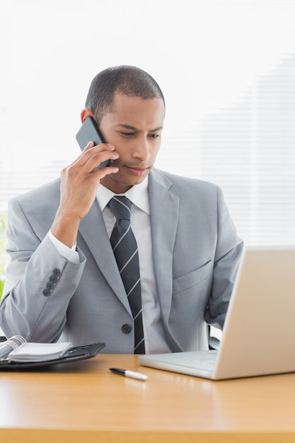 Geschäftsmann, der Laptop und Mobiltelefon im Büro verwendet