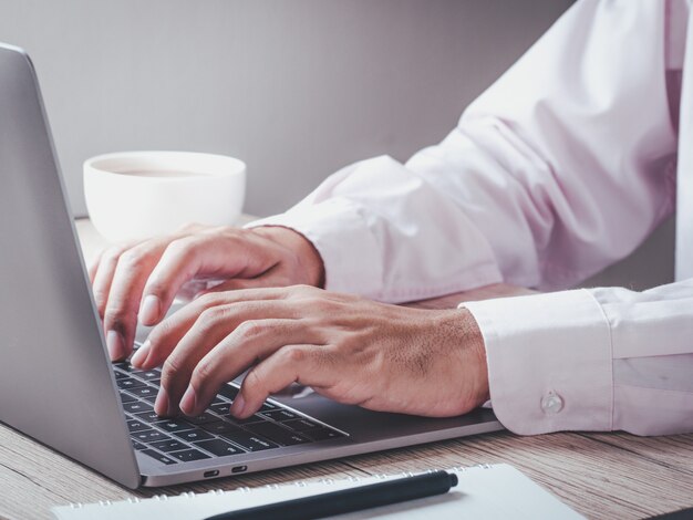 Geschäftsmann, der Laptop verwendet, der an der neuen Projektidee an seinem Schreibtisch im Büro am Morgen arbeitet