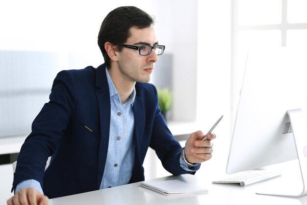 Geschäftsmann, der mit Computer im modernen Büro arbeitet. Kopfschuss eines männlichen Unternehmers oder Unternehmensleiters am Arbeitsplatz. Unternehmenskonzept.