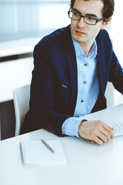 Geschäftsmann, der mit Computer im modernen Büro arbeitet. Kopfschuss eines männlichen Unternehmers oder Unternehmensleiters am Arbeitsplatz. Unternehmenskonzept.