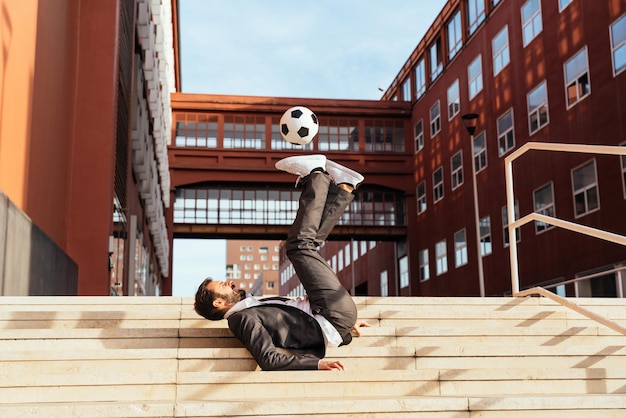 Geschäftsmann, der mit einem Fußball spielt und Freestyle-Tricks macht