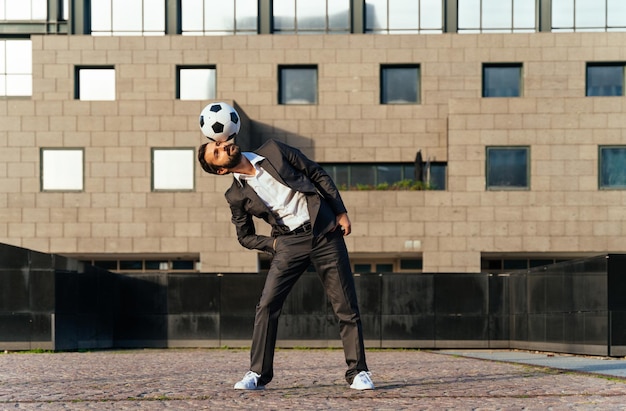 Geschäftsmann, der mit einem Fußball spielt und Freestyle-Tricks macht