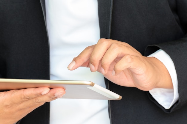 Geschäftsmann, der mit Handy oder Tablette im Büro arbeitet