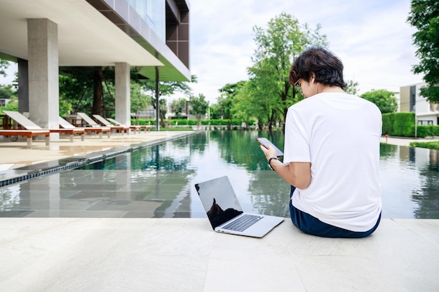 Geschäftsmann, der mit Laptop in der Nähe eines Swimmingpools in einem Landhotel arbeitet Freiberufler Reisender