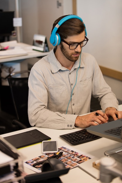 Geschäftsmann, der Musik durch Kopfhörer hört, während er im kreativen Büro arbeitet