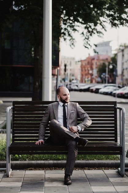 Geschäftsmann, der nach der Arbeit auf der Stadtstraße auf der Bank sitzt
