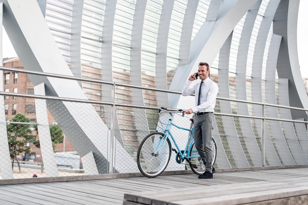 Geschäftsmann, der neben seinem alten Fahrrad steht und über den Mob spricht