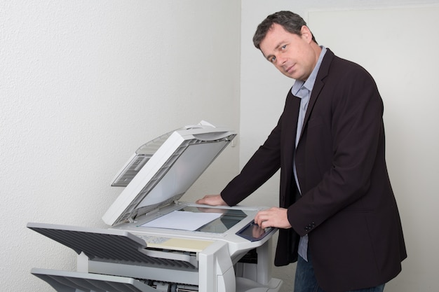 Geschäftsmann, der Papier auf Fotokopiergerät im Büro hält