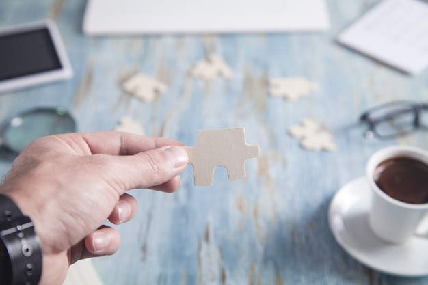 Geschäftsmann, der Puzzleteil am Schreibtisch zeigt.