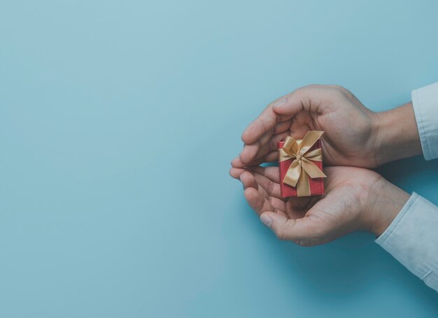 Geschäftsmann, der rote Geschenkbox mit Goldband für Geschenk zum Liebhaber, Frohe Weihnachten Frohes neues Jahr und Valentinstag Konzept hält.