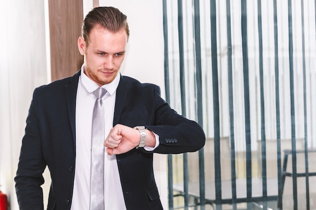 Geschäftsmann, der Uhr auf Bürogebäude betrachtet