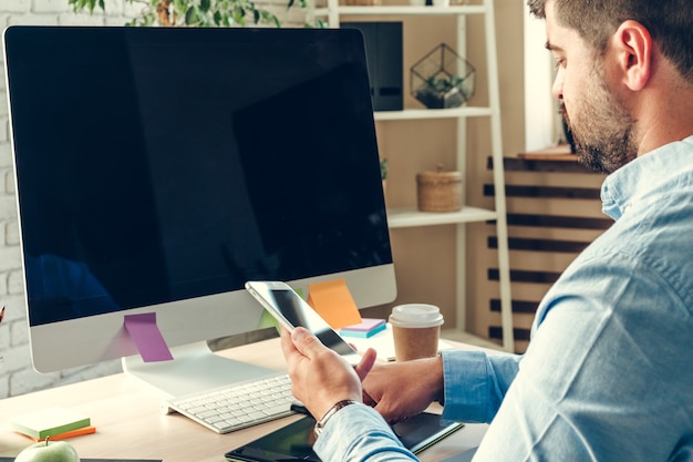 Geschäftsmann, der während des Arbeitstages im Büro auf Computermonitor schaut