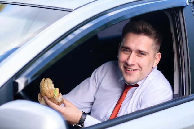 Geschäftsmann, der zu Mittag isst und Kaffee im Auto trinkt.