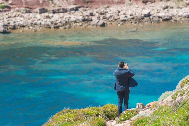 Geschäftsmann fotografiert mit Smartphone an der Küste