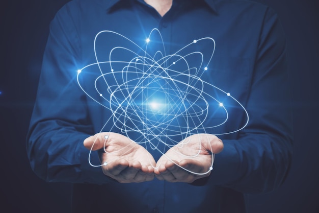 Geschäftsmann hält Atom auf dunklem Hintergrund Wissenschaftskonzept