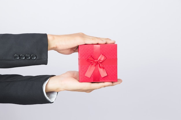Geschäftsmann hält den roten Kasten des Geschenks, lokalisierten Hintergrund aus