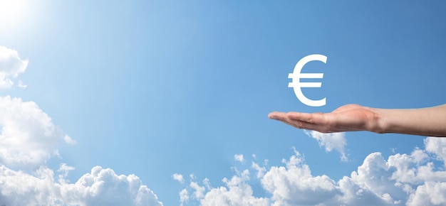 Geschäftsmann hält Geldmünzen-Symbole EUR oder Euro auf dunklem Hintergrund. Wachsendes Geldkonzept für Unternehmensinvestitionen und Finanzen