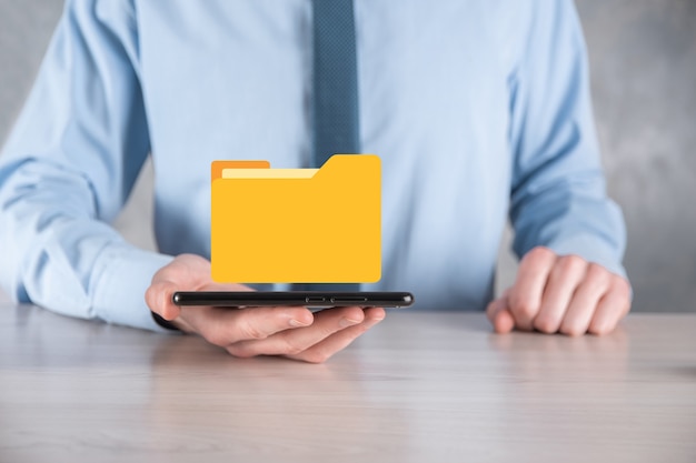 Geschäftsmann hält Ordnersymbol. Dokumentenverwaltungssystem oder DMS-Setup von IT-Berater mit modernem Computer suchen nach Verwaltungsinformationen und Unternehmensdateien. Geschäftsabwicklung,