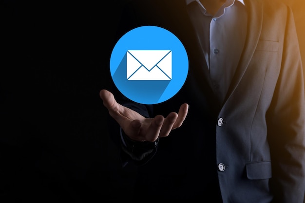 Geschäftsmann Hand, die Briefsymbol, E-Mail-Symbole hält. Kontaktieren Sie uns per Newsletter-E-Mail und schützen Sie Ihre persönlichen Daten vor Spam-Mail. Kundenservice-Callcenter kontaktieren Sie uns. E-Mail-Marketing-Newsletter.