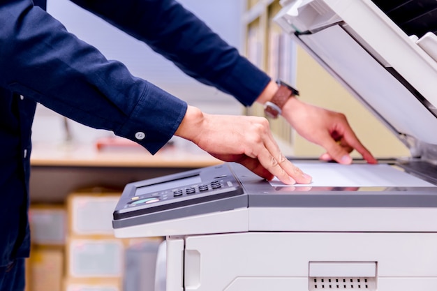 Geschäftsmann Handpresseknopf auf Platte des Druckers, Druckerscannerlaser-Bürokopiermaschinenversorgungen beginnen Konzept.