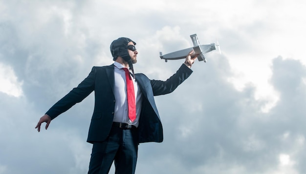 Geschäftsmann im Anzug und Pilotenhut starten Flugzeug Spielzeug auf Himmelshintergrund Bestrebungen