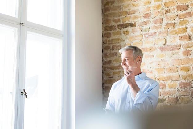 Geschäftsmann im Büro am Fenster mit Freisprecheinrichtung