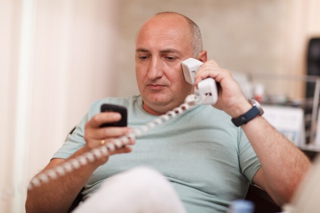 Geschäftsmann im Büro, das an zwei Telefonen spricht