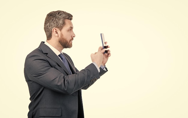 Geschäftsmann im Business-Anzug zeigt mit dem Finger auf das Handy, das auf dem weißen Kopierraum zeigt